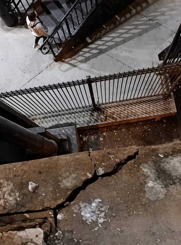 Concrete already breaking apart over active pedestrian space — people walking directly below at the Chicago Riverwalk near Wacker and Columbus, 820pm April 28 2026 SubX.News®